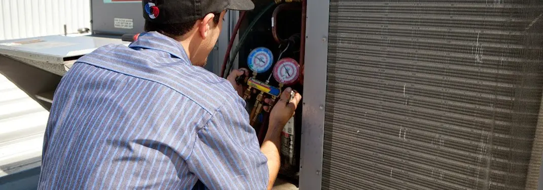 HVAC technician servicing a condenser unit in Woodstock