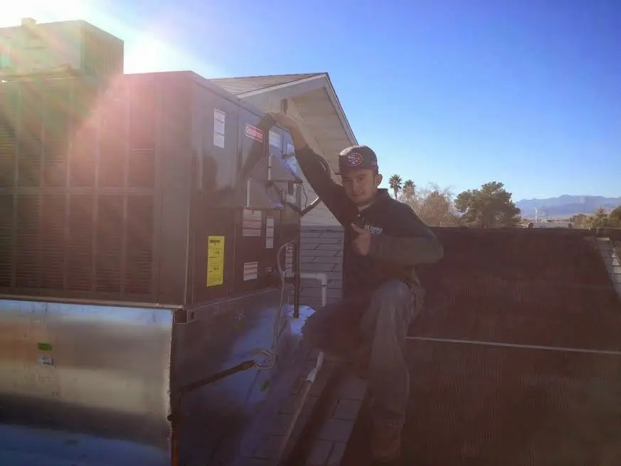 HVAC technician performing Air Duct Repair on a rooftop unit in Woodstock